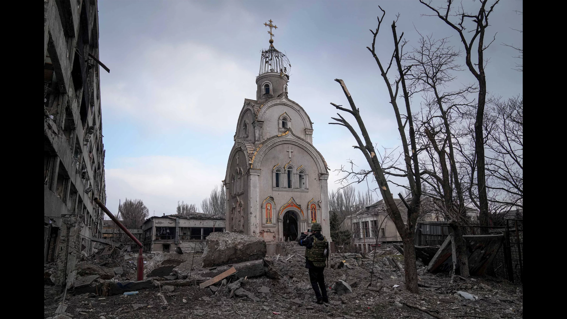 Украинский солдат фотографирует церковь, разрушенную во время артиллерийского обстрела жилого района Мариуполя, Украина, 10 марта 2022 г.