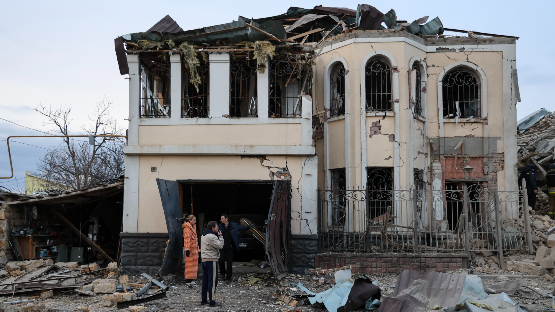 Cold Ukrainians in front of a house destroyed during the war with Russia.